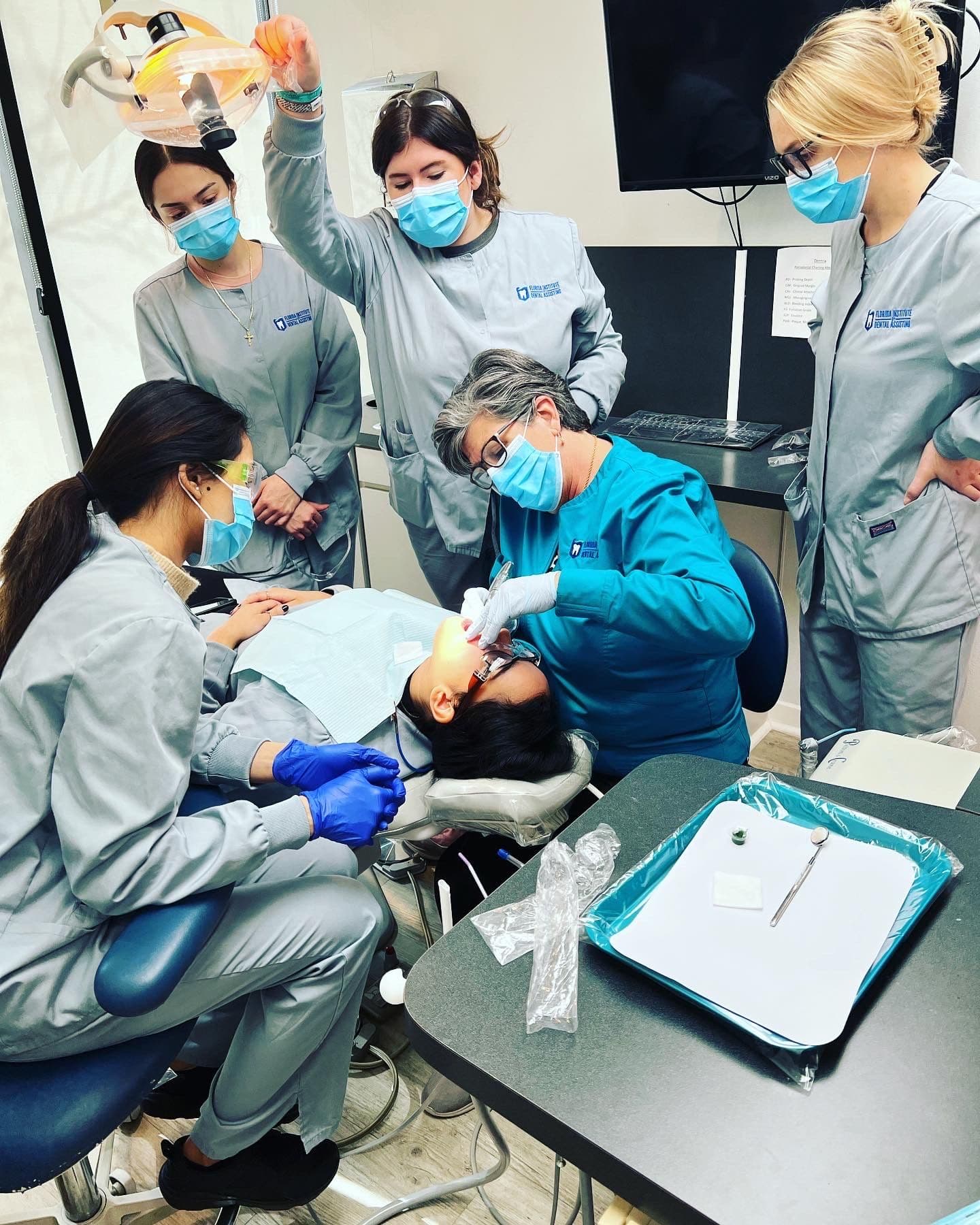 FIDA instructor working chairside while four dental assisting students observe during hands-on training in Jacksonville