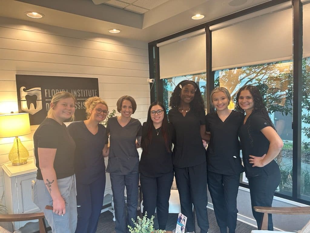 A cohort of FIDA dental assisting students under the Florida Institute of Dental Assisting sign